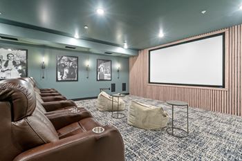a theater room with leather couches and a projector screen